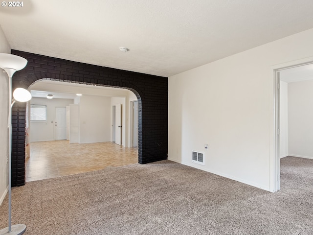 carpeted spare room featuring brick wall