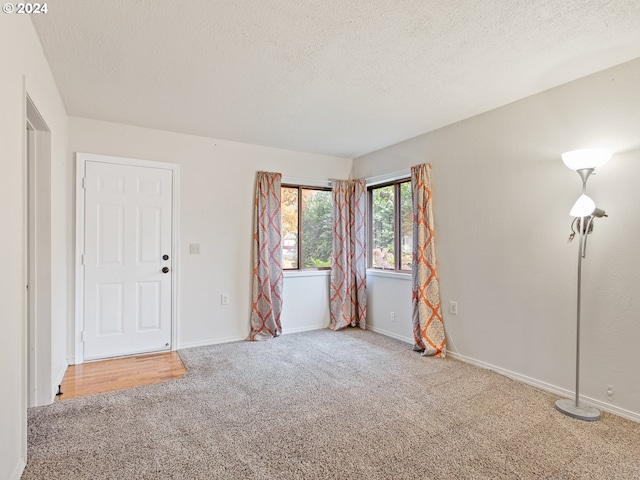 carpeted spare room with a textured ceiling