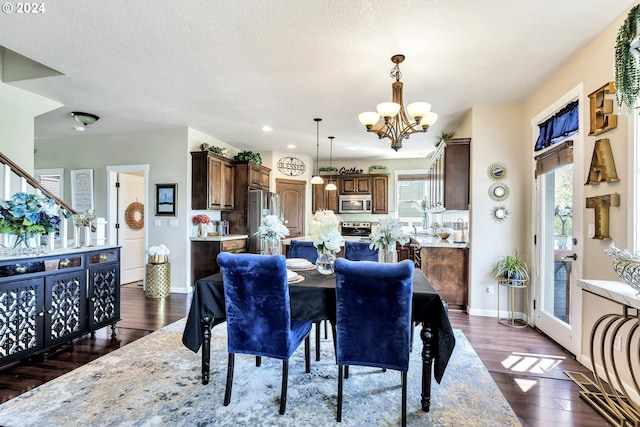 dining space featuring an inviting chandelier, a textured ceiling, and dark wood-type flooring