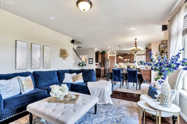 living room featuring light wood-type flooring, a textured ceiling, and a chandelier