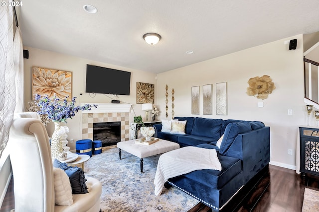 living room featuring dark wood-type flooring and a tiled fireplace