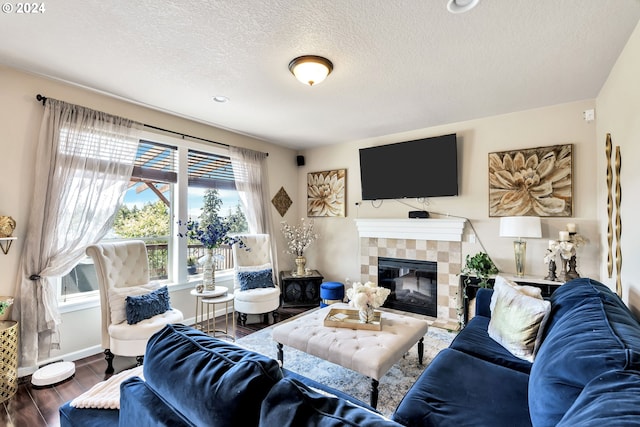 living room with hardwood / wood-style flooring, a tile fireplace, and a textured ceiling