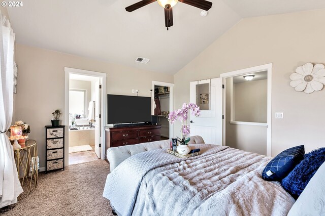 carpeted bedroom with a walk in closet, ensuite bath, vaulted ceiling, and ceiling fan