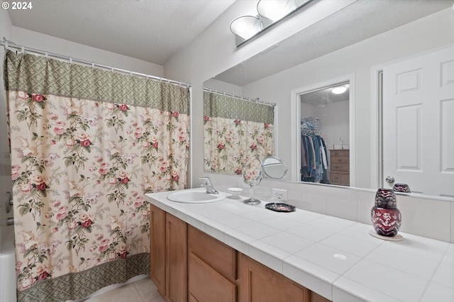 bathroom with tile patterned flooring, a textured ceiling, and vanity