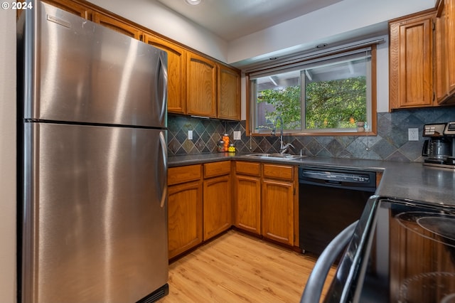 kitchen featuring tasteful backsplash, sink, black appliances, and light hardwood / wood-style flooring