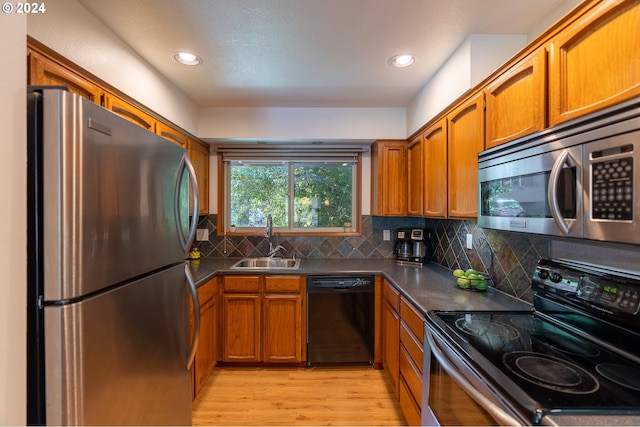 kitchen featuring black appliances, light hardwood / wood-style floors, sink, and tasteful backsplash