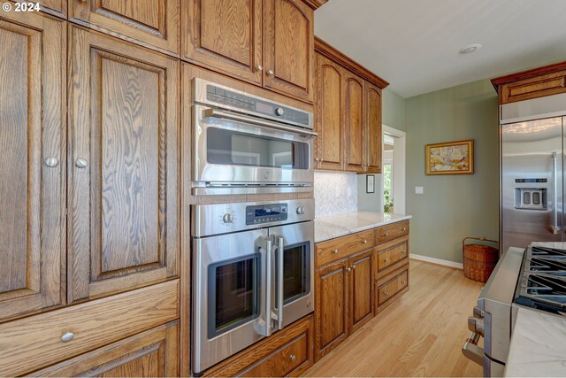 kitchen featuring light stone counters, stainless steel appliances, and light wood-type flooring