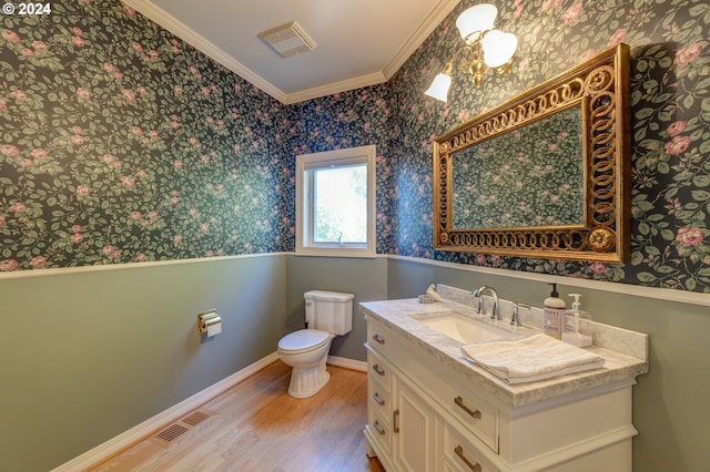 bathroom featuring wood-type flooring, vanity, ornamental molding, and toilet