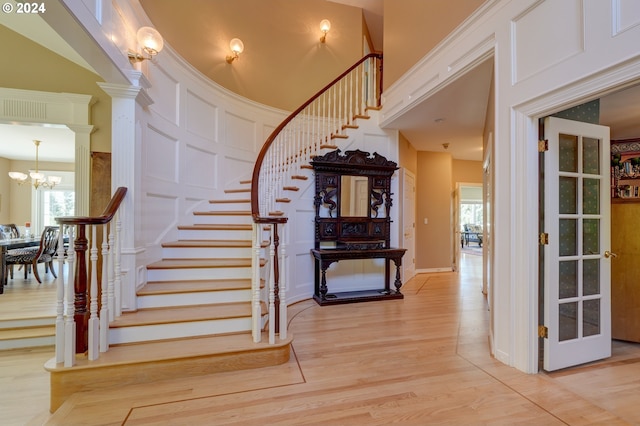 stairs with a notable chandelier, a towering ceiling, hardwood / wood-style floors, and a healthy amount of sunlight