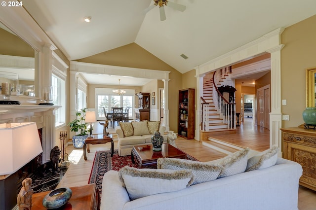 living room with decorative columns, light hardwood / wood-style floors, ceiling fan, and high vaulted ceiling