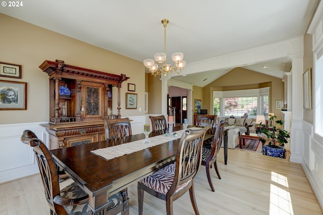 dining area with lofted ceiling, light wood-type flooring, a chandelier, and decorative columns