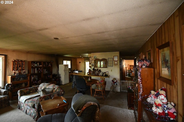 carpeted living room featuring wooden walls and a textured ceiling