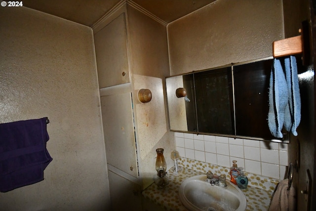 bathroom featuring a textured wall, tasteful backsplash, and a sink