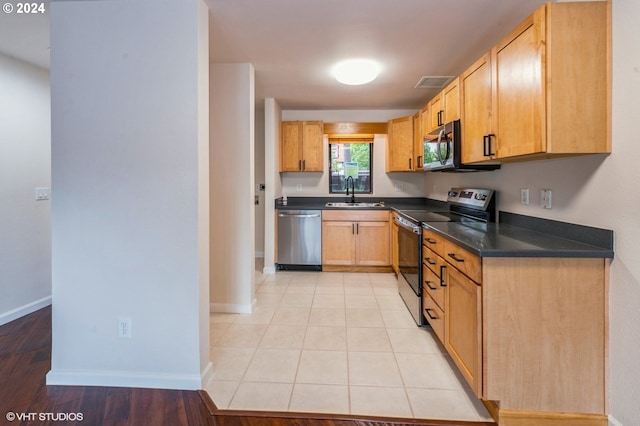 kitchen with light hardwood / wood-style floors, appliances with stainless steel finishes, sink, and light brown cabinets