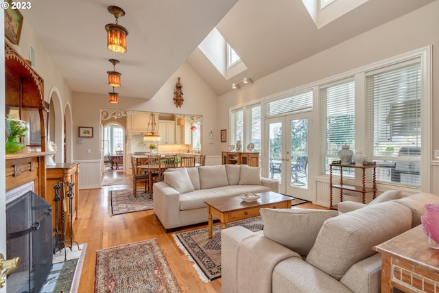 living room featuring a skylight, a healthy amount of sunlight, light hardwood / wood-style floors, and french doors