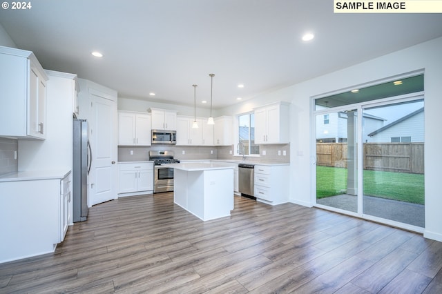 kitchen featuring white cabinetry, light hardwood / wood-style flooring, decorative light fixtures, a kitchen island, and appliances with stainless steel finishes