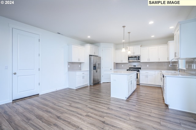 kitchen with white cabinets, light hardwood / wood-style floors, decorative light fixtures, a kitchen island, and stainless steel appliances