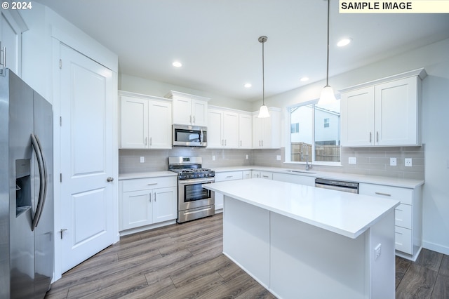 kitchen with stainless steel appliances, white cabinetry, hanging light fixtures, and hardwood / wood-style flooring