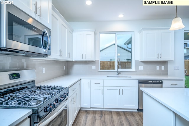 kitchen featuring white cabinetry, sink, hanging light fixtures, stainless steel appliances, and light hardwood / wood-style floors