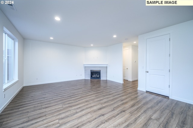 unfurnished living room featuring light hardwood / wood-style floors and a tiled fireplace