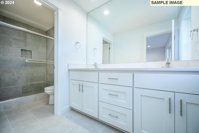 bathroom with tile patterned floors, vanity, toilet, and a shower with door