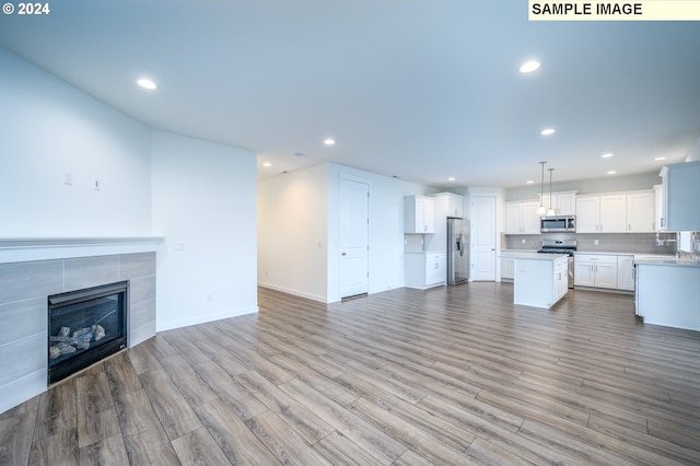 unfurnished living room with a tiled fireplace and light hardwood / wood-style floors