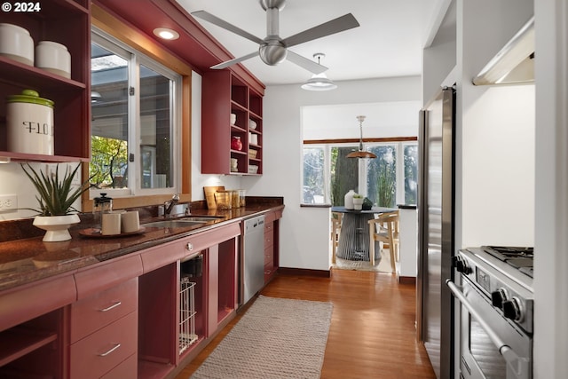 kitchen with stainless steel appliances, sink, dark stone counters, decorative light fixtures, and dark wood-type flooring