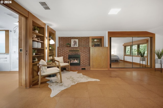 sitting room with built in features, a brick fireplace, and tile patterned floors