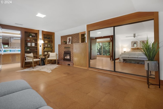 living room featuring ceiling fan and a brick fireplace