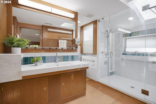 bathroom featuring tile walls, walk in shower, a skylight, and vanity