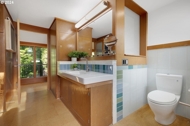 bathroom featuring toilet, vanity, and tile walls