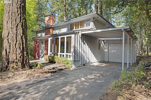 view of front of property featuring a chimney, an attached carport, and driveway