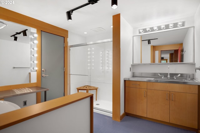 bathroom featuring a shower with shower door and vanity