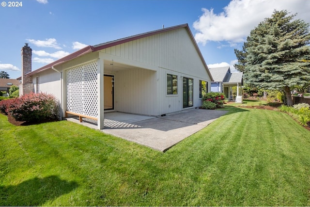 back of house featuring a lawn and a patio area