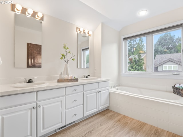 bathroom featuring vanity, hardwood / wood-style floors, and tiled bath