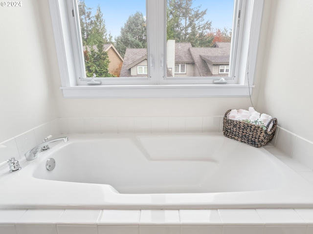 bathroom featuring a wealth of natural light and tiled bath