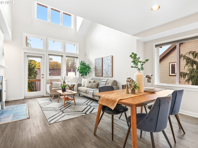 dining room with dark hardwood / wood-style flooring, a towering ceiling, and plenty of natural light