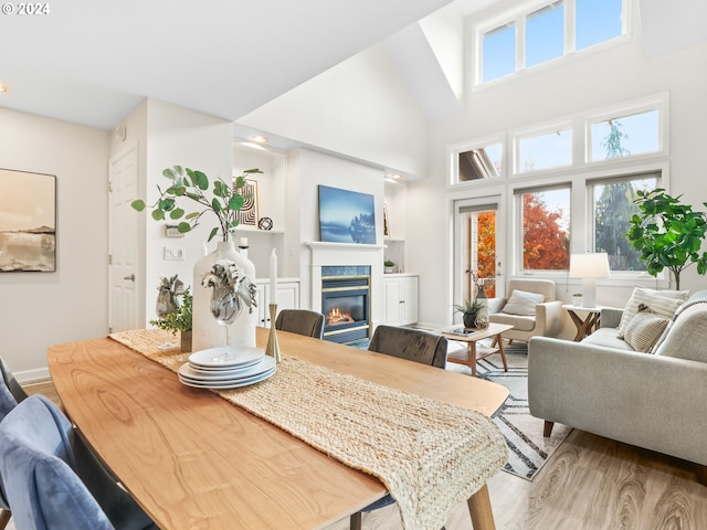 dining space with a towering ceiling, a healthy amount of sunlight, and light hardwood / wood-style floors