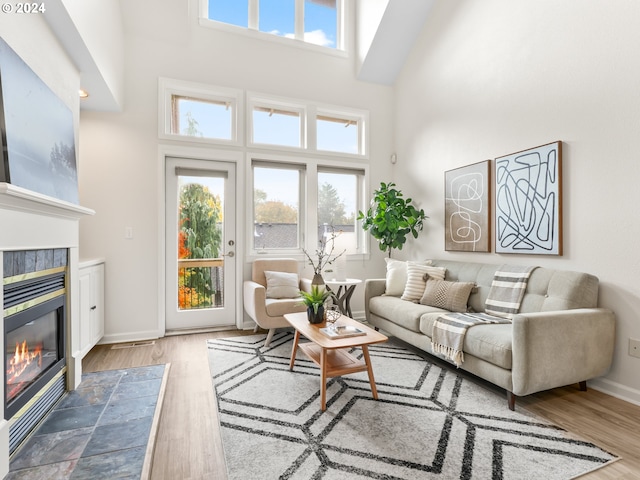 living room featuring a healthy amount of sunlight, a tiled fireplace, and a towering ceiling