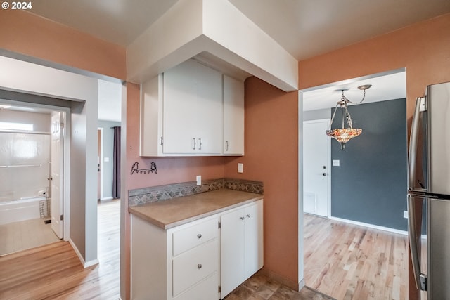 kitchen with stainless steel refrigerator, light hardwood / wood-style flooring, white cabinets, and pendant lighting