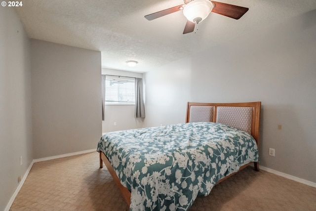 carpeted bedroom featuring ceiling fan and a textured ceiling