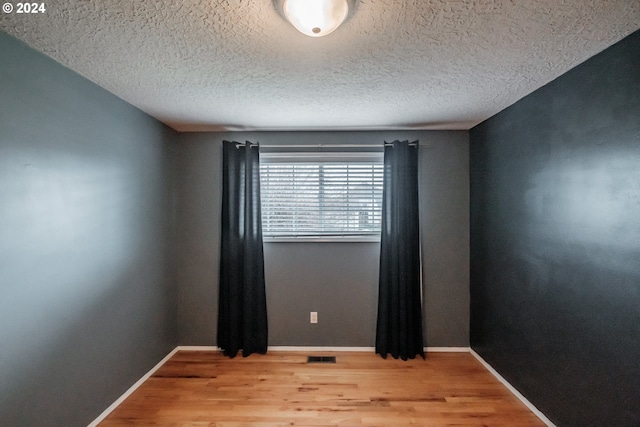 spare room with a textured ceiling and light wood-type flooring