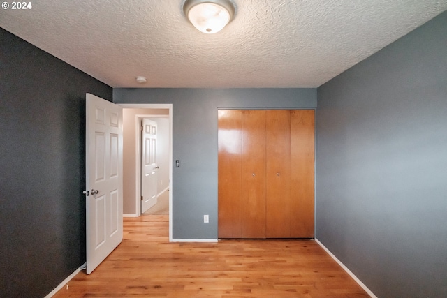 unfurnished bedroom featuring a closet, light hardwood / wood-style flooring, and a textured ceiling