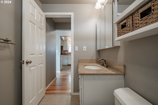 bathroom with toilet, vanity, and hardwood / wood-style flooring