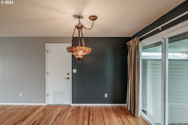 unfurnished dining area with a textured ceiling and light wood-type flooring