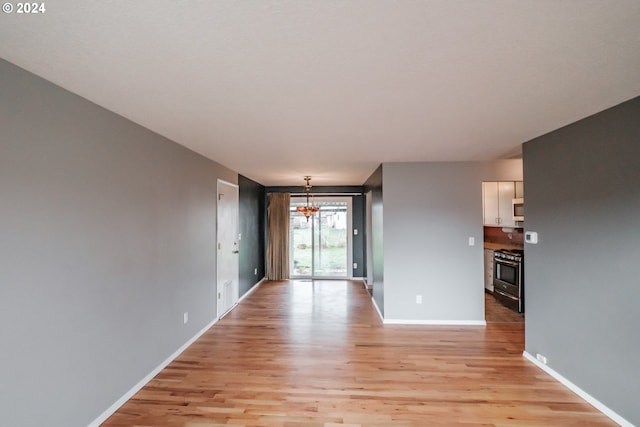 empty room featuring an inviting chandelier and light hardwood / wood-style flooring