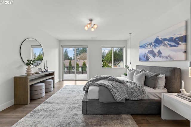 bedroom with hardwood / wood-style floors, access to outside, and a chandelier