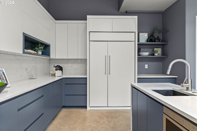 kitchen with white cabinetry, sink, light stone countertops, stainless steel dishwasher, and blue cabinets