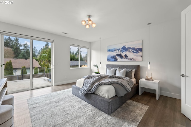 bedroom featuring access to exterior, hardwood / wood-style flooring, and a chandelier