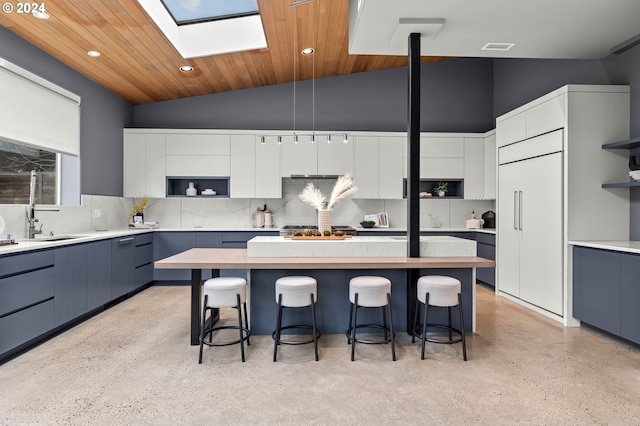 kitchen with a center island, white cabinets, sink, a kitchen bar, and wood ceiling